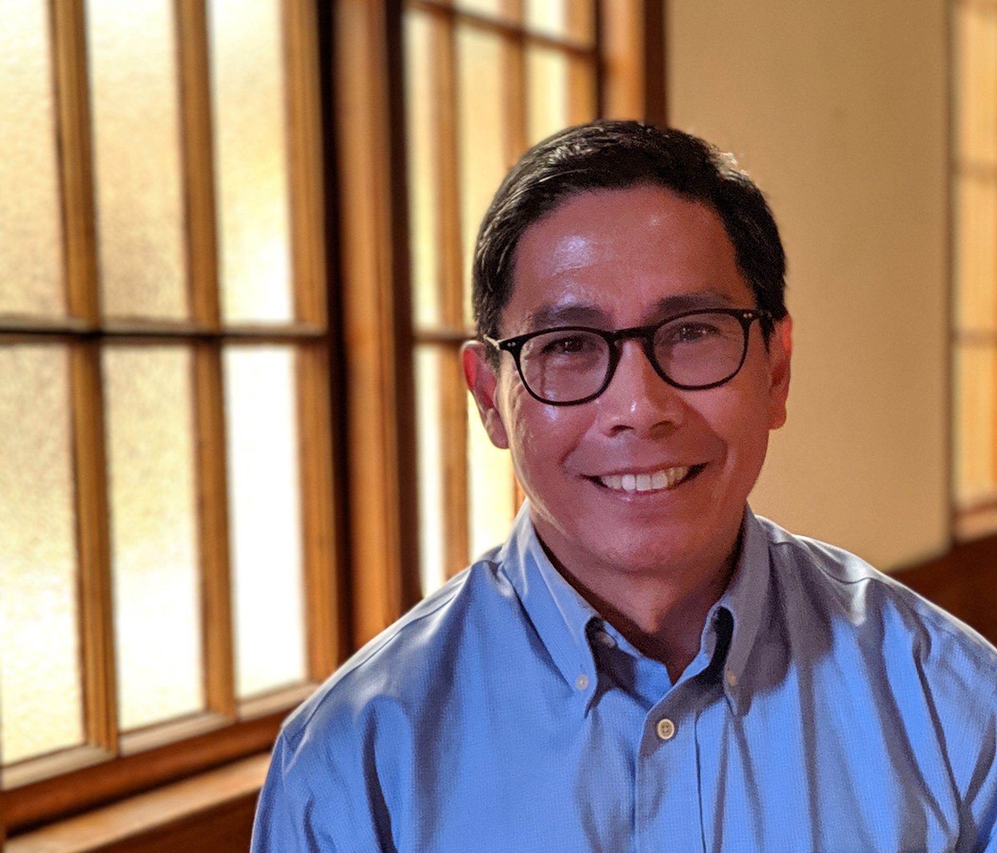 A photo of Ignacio Dayrit in a blue button up shirt smiling.