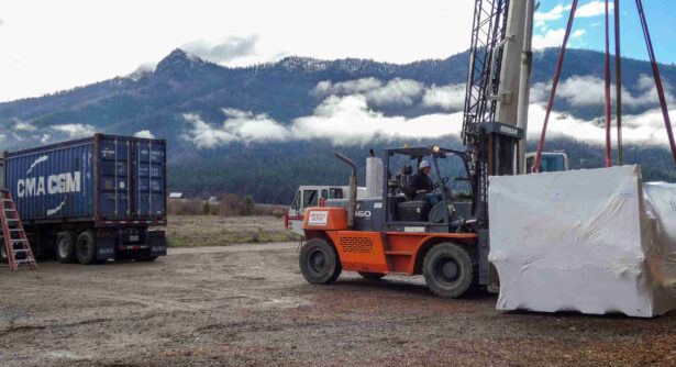 Forklift and crane delivering shrink-wrapped equipment at the IVWUC