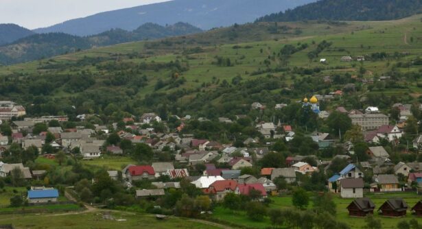 aerial photo of Ounalashka Alaska showing buildings in a valley surrounded by green hills and mountains in the distance