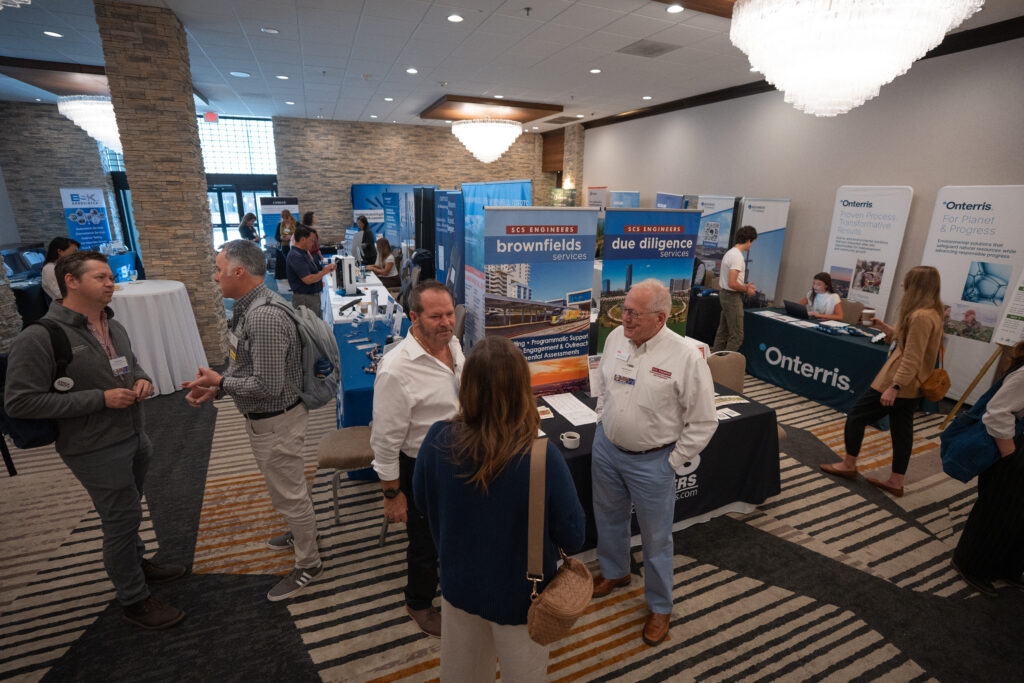 People stand and talk in front of exhibit booths at the California Land Recycling Conference